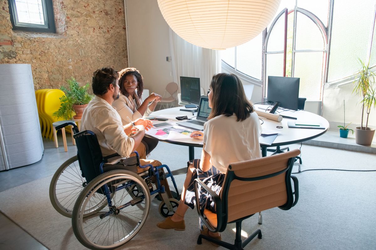 Cuatro personas reunidas en una oficina; una de ellas utiliza silla de ruedas